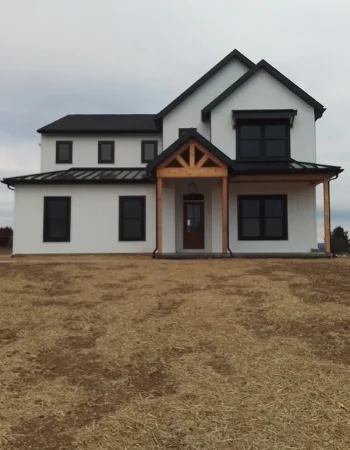A modern white farmhouse with black trim features a prominent rustic wood-framed front porch