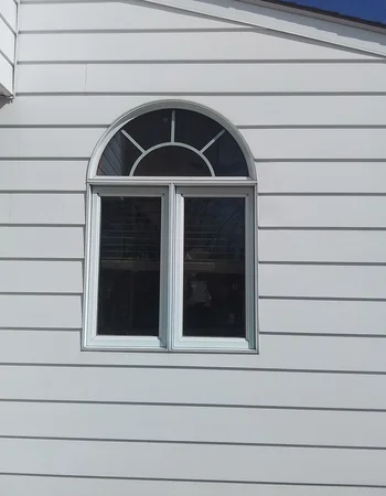 New board-and-batten siding installation with decorative arched window in Compass, PA