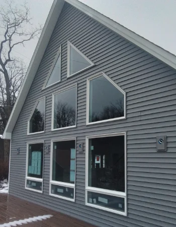 A gray-sided gable end features a complex, staggered arrangement of large geometric windows